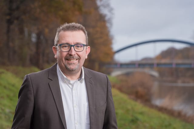 Matthias Brinkmann steht am Stichkanal. Im Hintergrund eine Brücke.